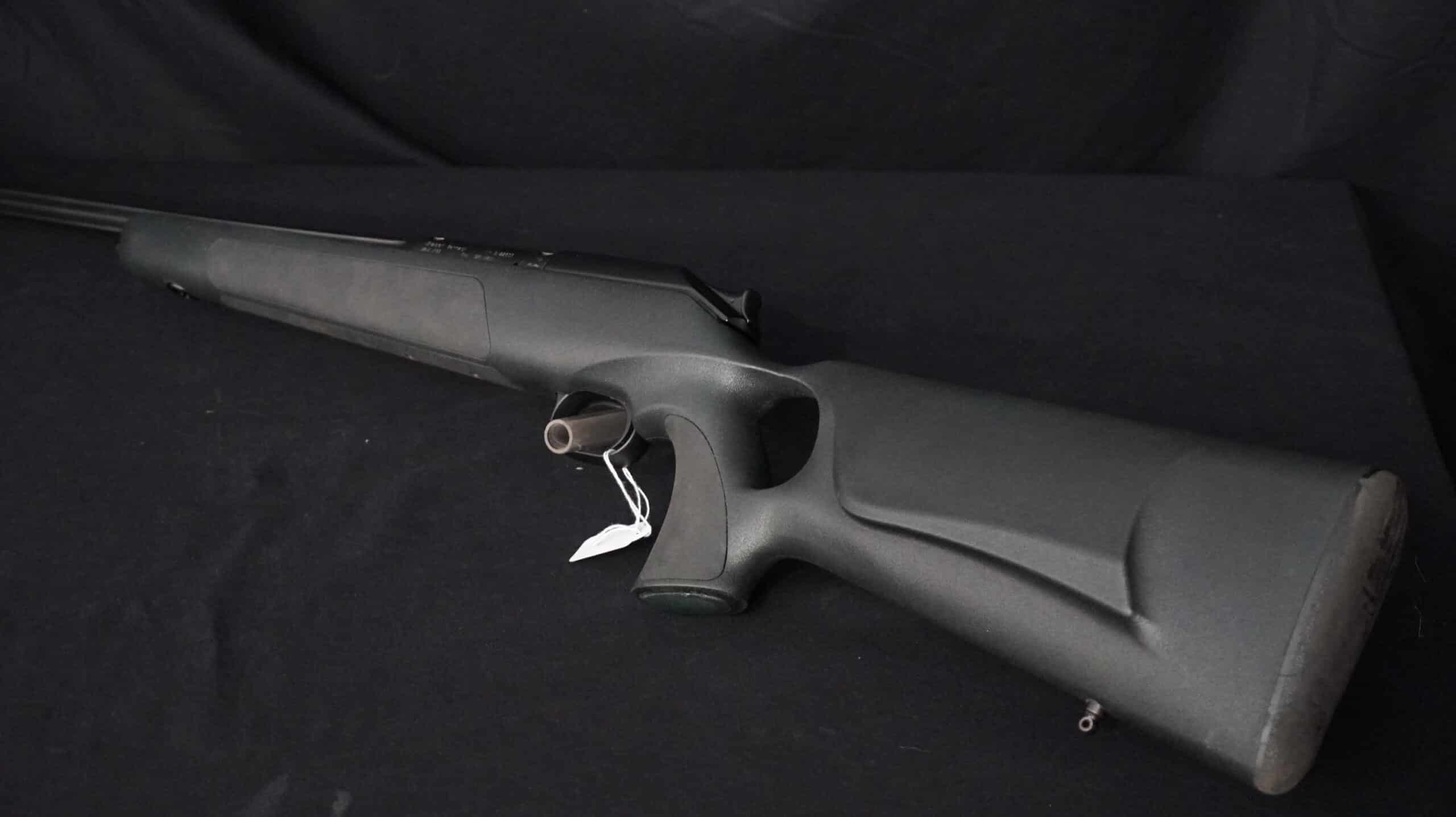 Carabine moderne de chasse ou de sport au fini mat foncé, vue de profil, avec étiquette blanche attachée à la détente.