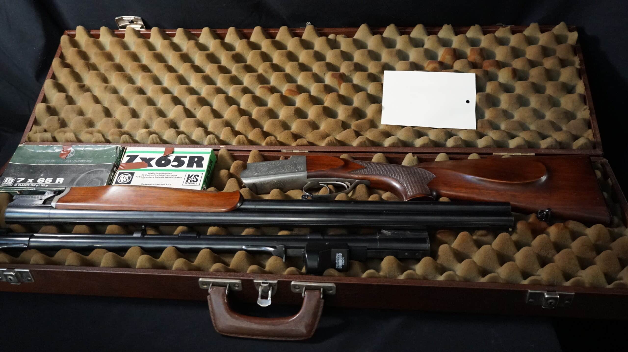 Mallette ouverte marron avec fusil juxtaposé démonté, cartouches 7x65R, et mousse alvéolée.