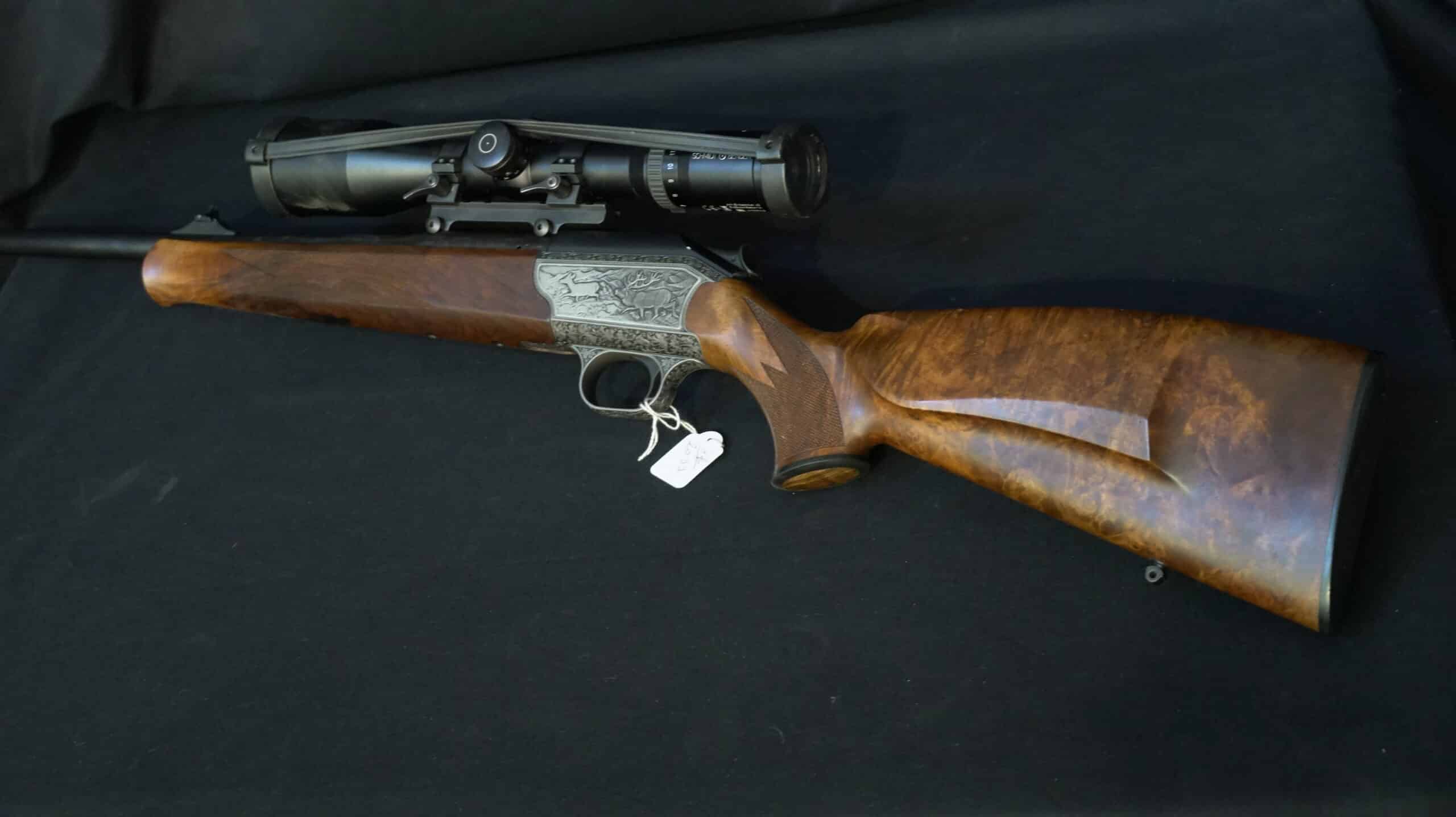 Carabine de chasse haut de gamme avec lunette Schmidt & Bender, gravures animalières et crosse en bois de luxe.