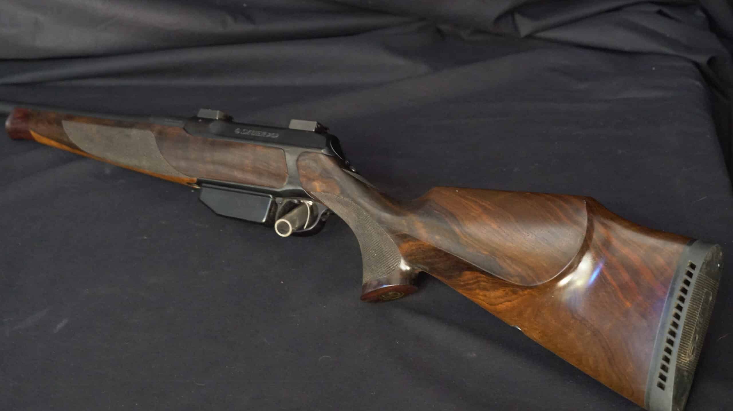 Carabine Sauer 202 avec crosse en bois de luxe veiné sur fond noir, marquage SAUER 202 visible.