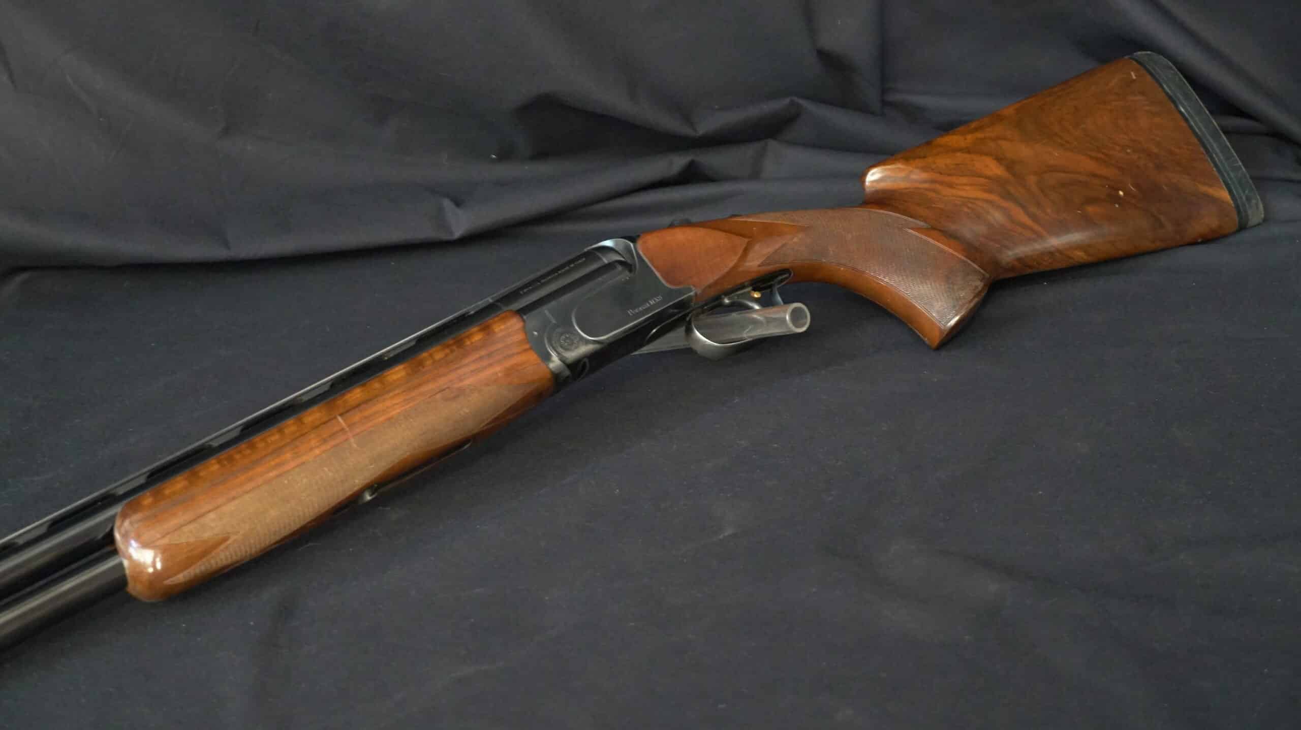 Fusil de chasse superposé Perazzi MX8 avec crosse en bois précieux sur fond noir.